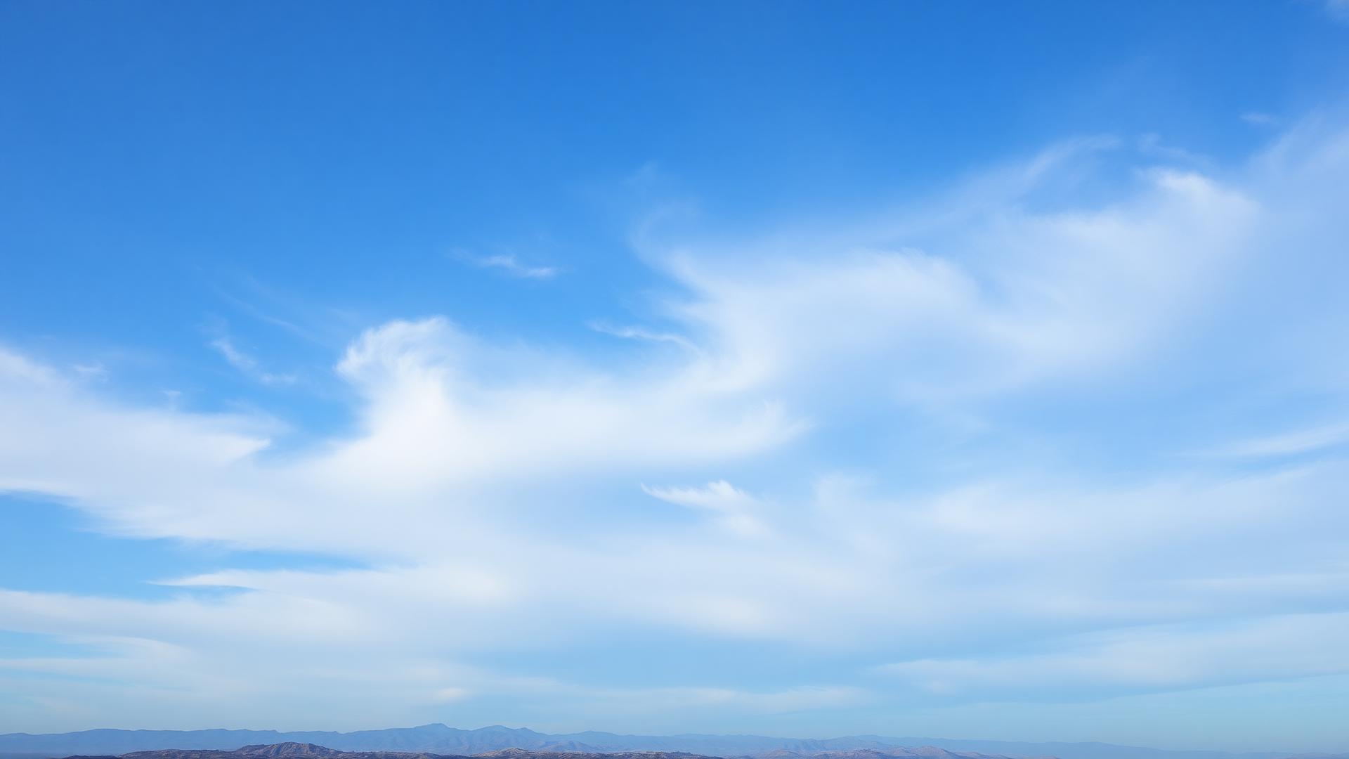 Cielo abierto con nubes sobre un horizonte de montañas